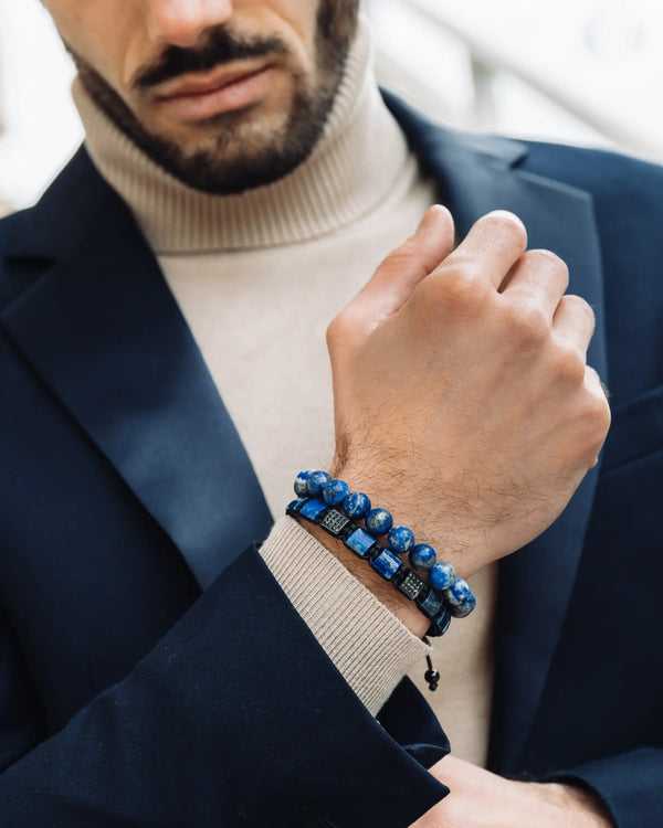 Man’s wrist wearing blue lapis beaded bracelet with black cord and small charm detail