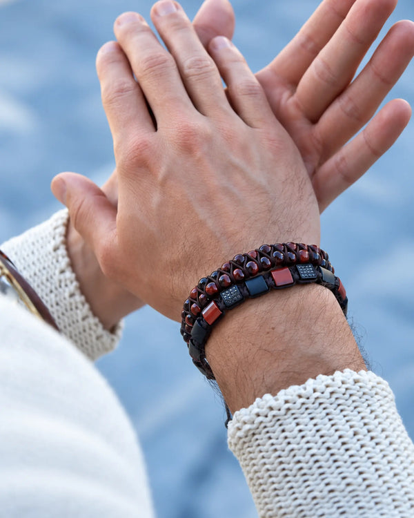 Woven beaded bracelet on wrist with dark navy and burgundy beads, black clasp segments