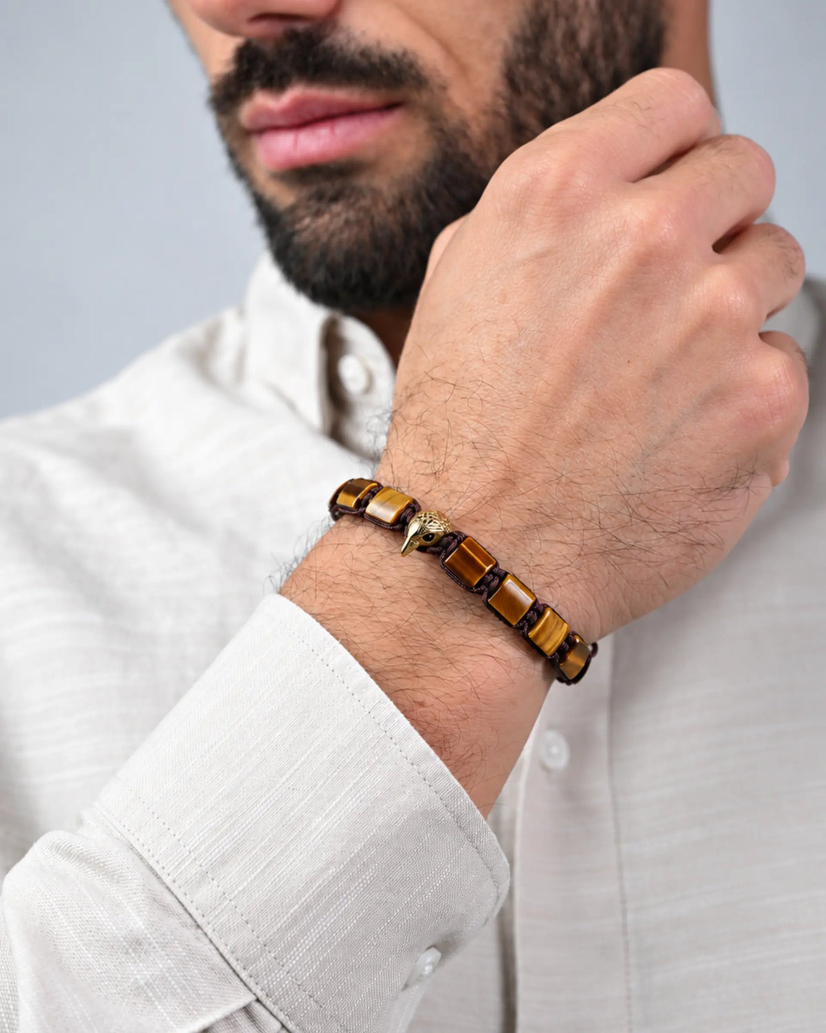 Man wearing brown stone bead bracelet with gold-tone beads on wrist