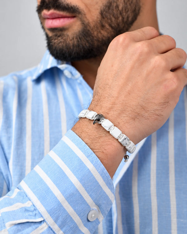 Howlite beaded bracelet on wrist with silver falcon charm and white adjustable cord