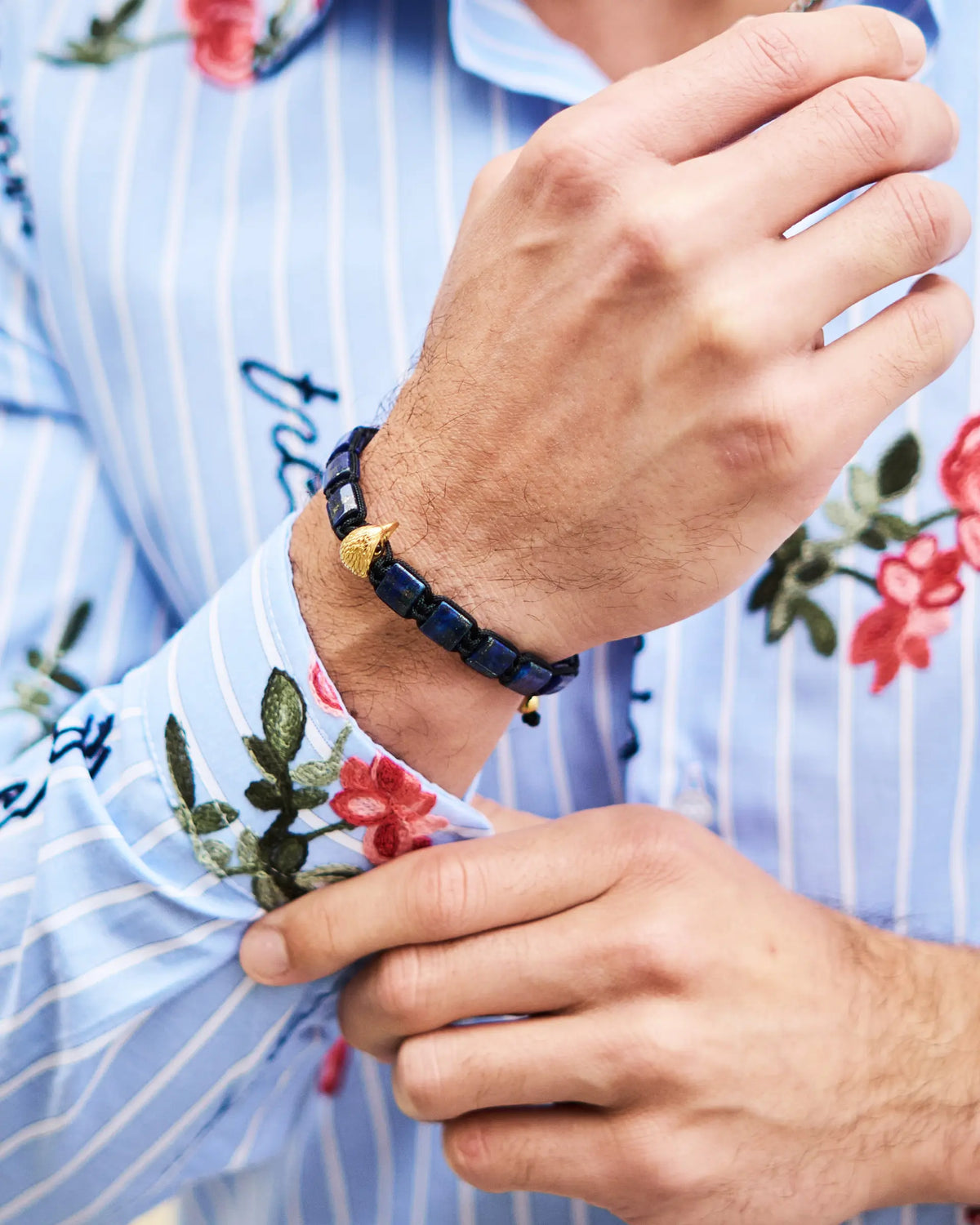 Lapis lazuli beaded bracelet with gold falcon charm on a wrist