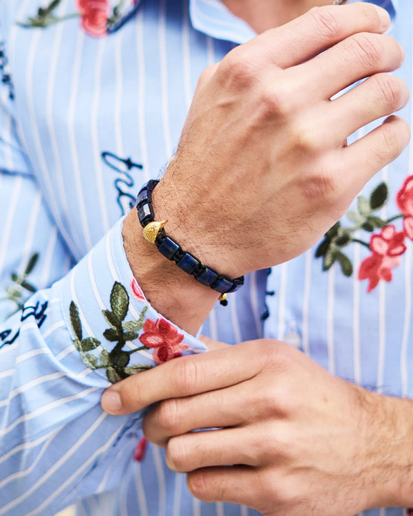 Lapis lazuli beaded bracelet with gold falcon charm on a wrist