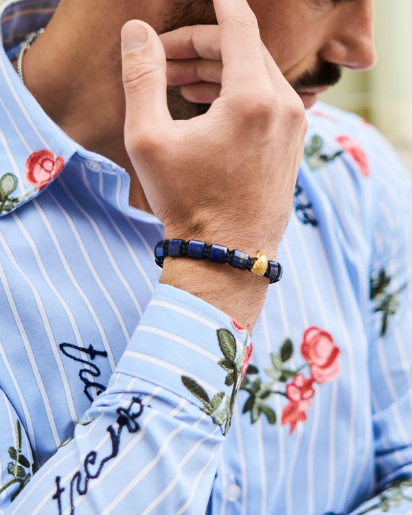 Lapis lazuli beaded bracelet with gold falcon charm worn on forearm