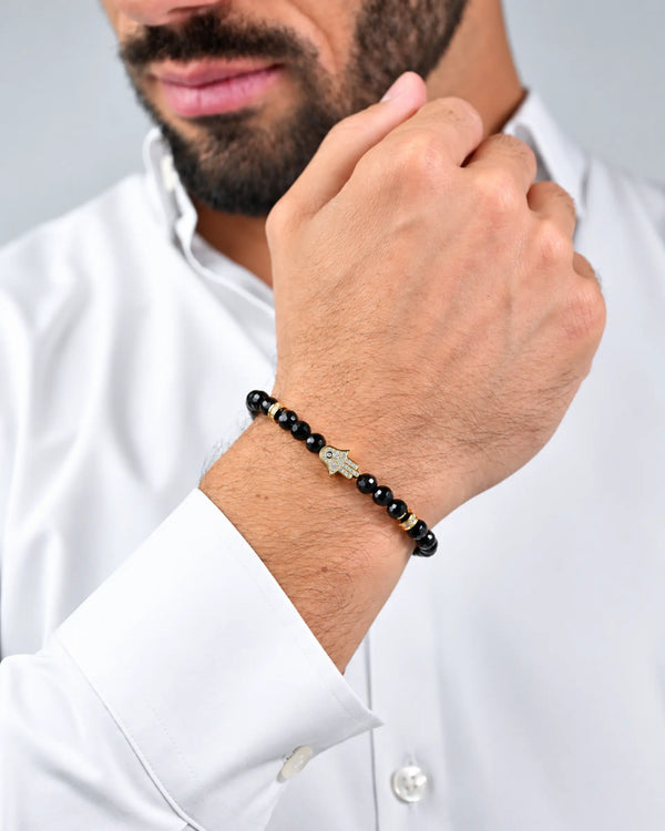 Black onyx bead hamsa bracelet with gold charm beads and black cord, adjustable