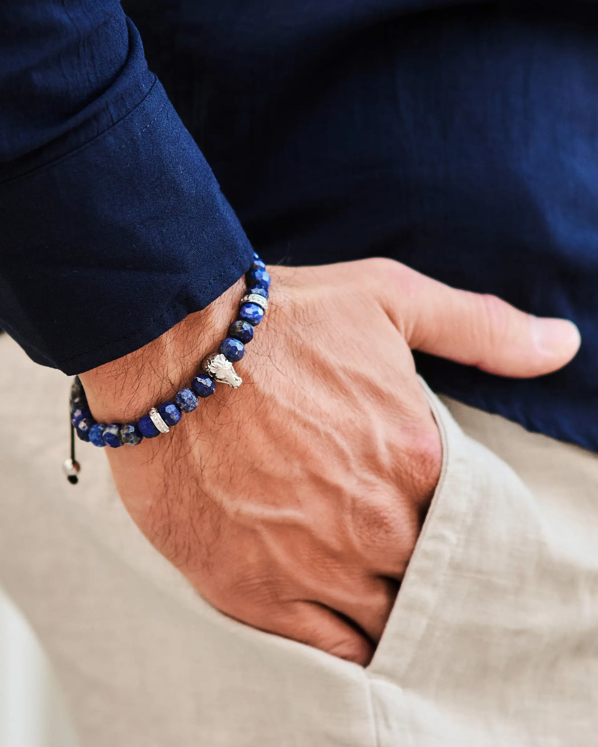 Lapis lazuli bead bracelet on wrist with silver horse charm and black cord