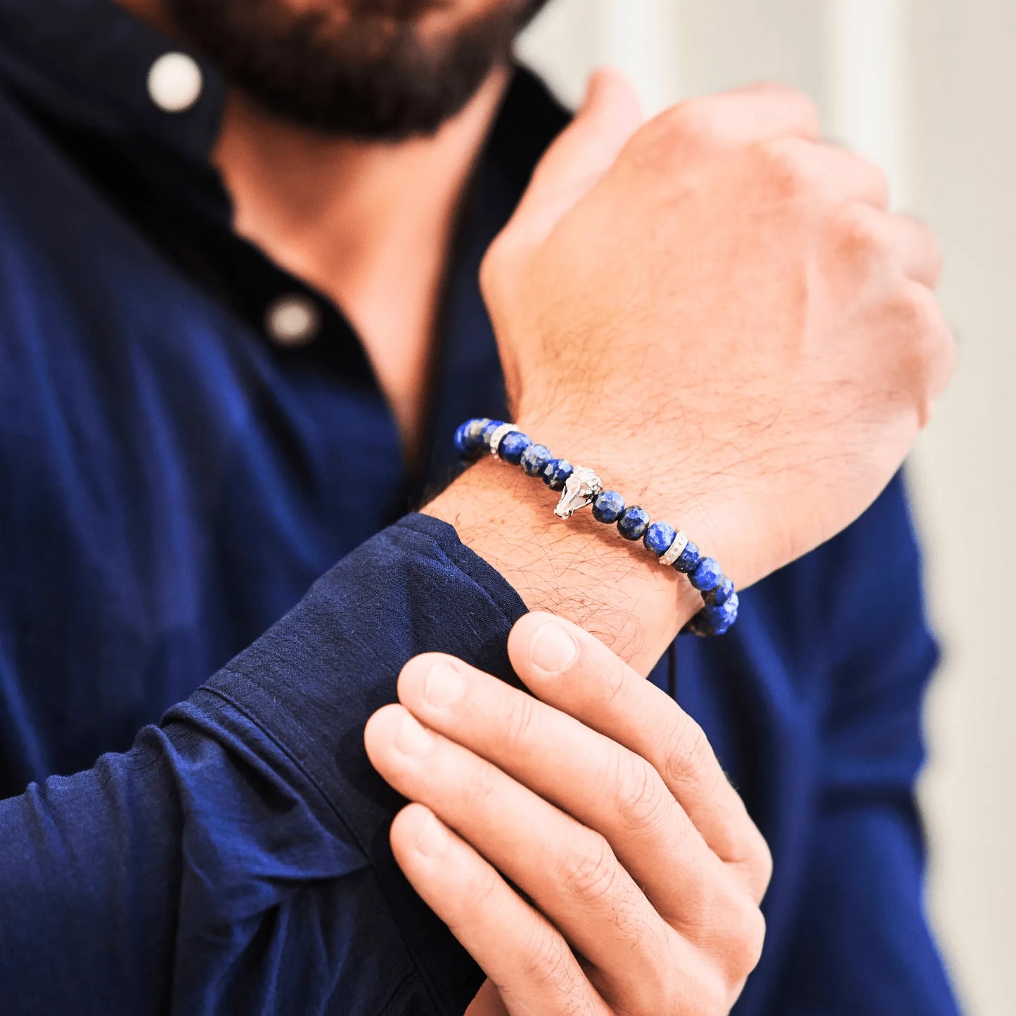 Man wearing blue gemstone beaded bracelet with silver horse head charm”