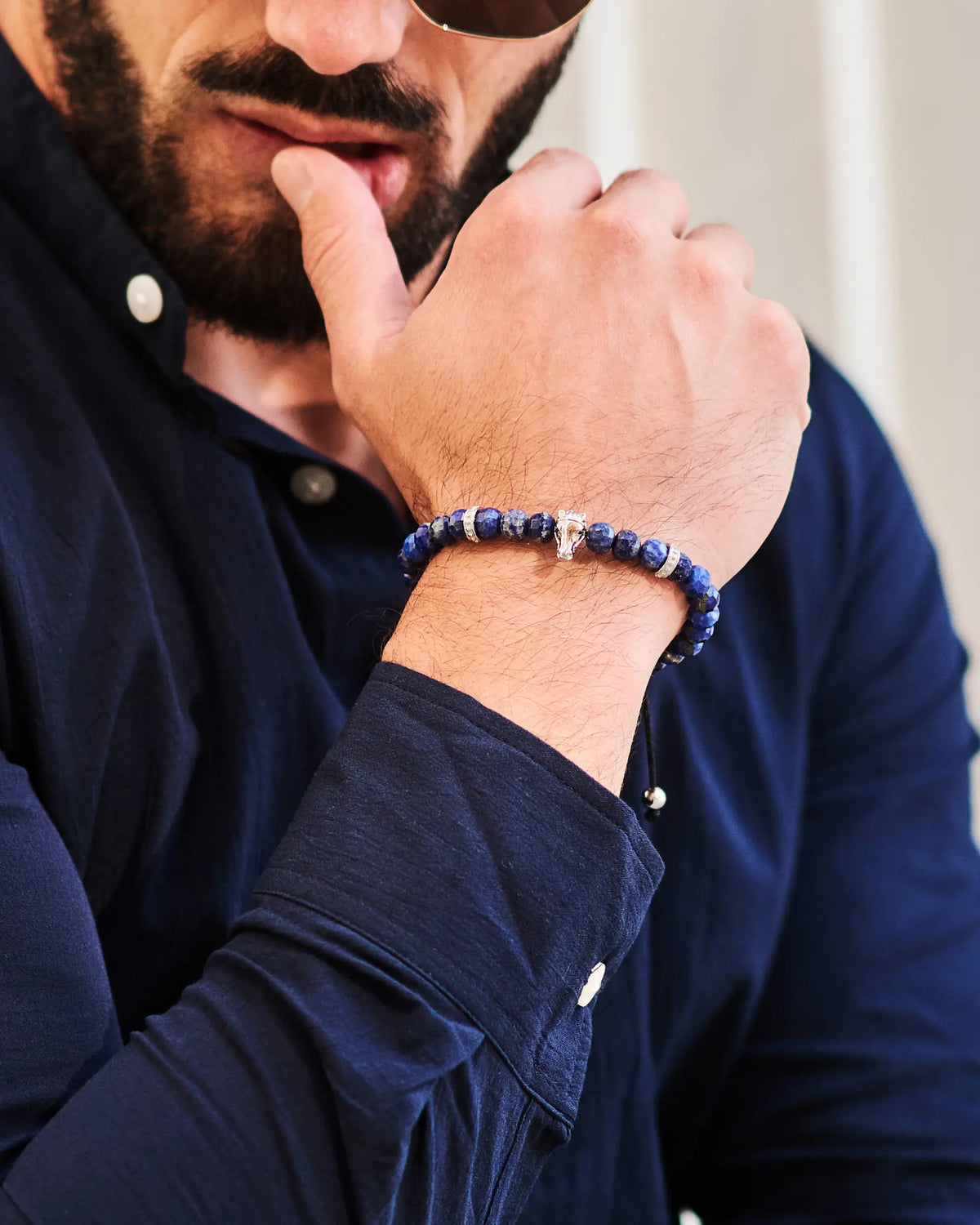 Lapis lazuli bead bracelet on wrist with silver horse charm and black cord