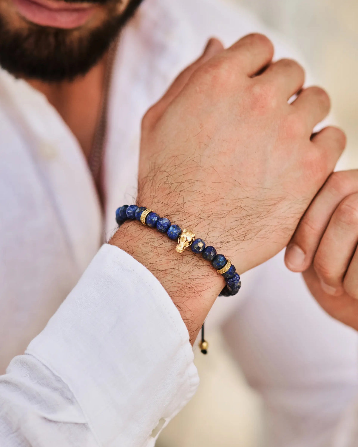 Lapis lazuli bracelet on wrist, blue beads with gold-tone accents and horse charm