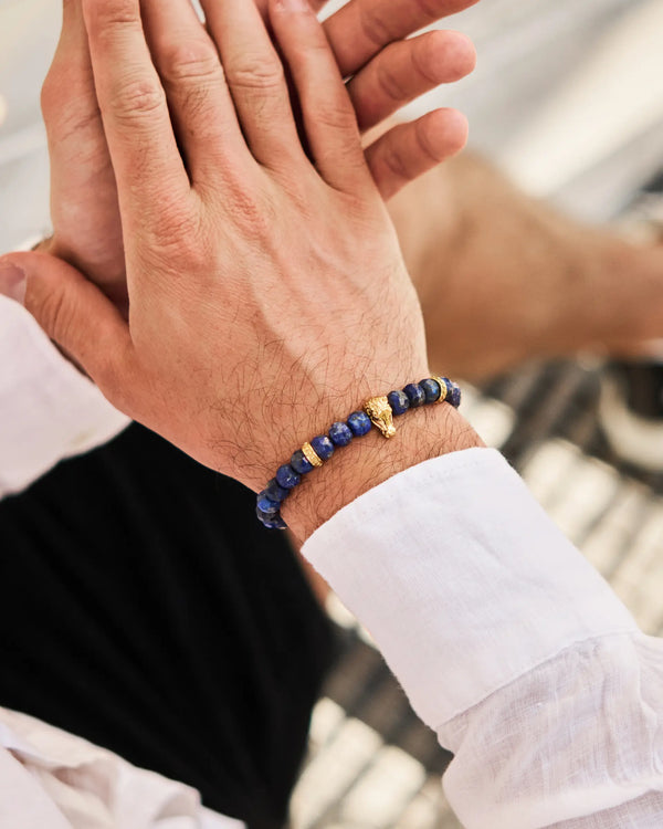 Lapis lazuli bead bracelet on wrist with black cord and gold-tone horse charm