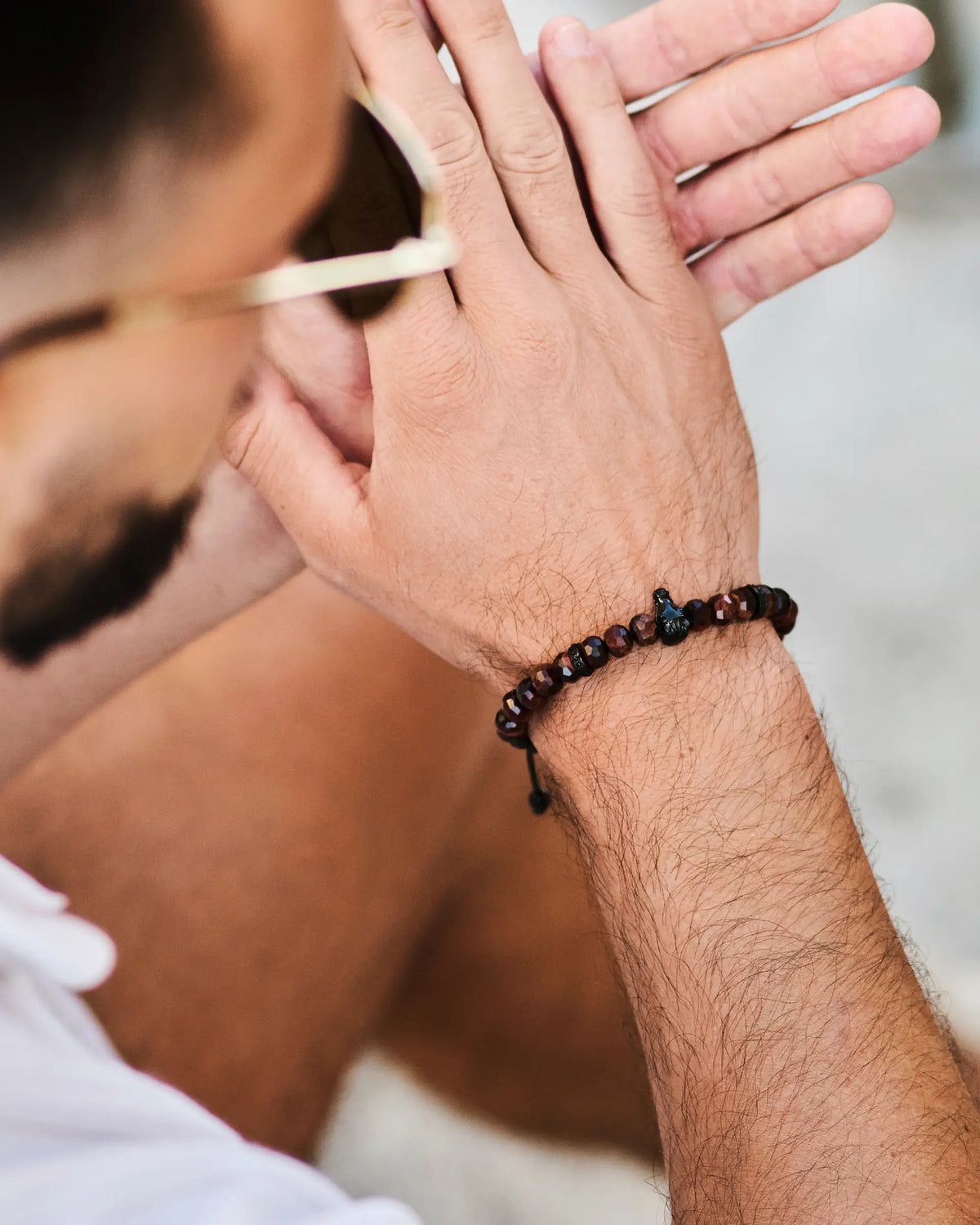 Beaded bracelet on man's wrist with black beads and red-orange faceted beads