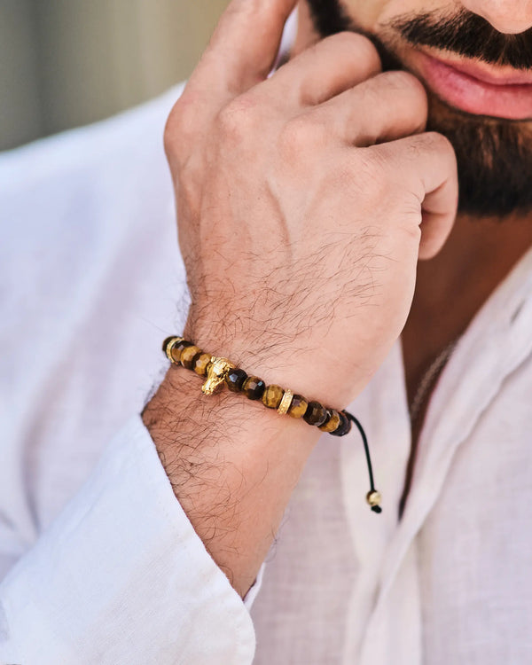 Tiger eye bead horse bracelet on wrist, black cord tied at back.