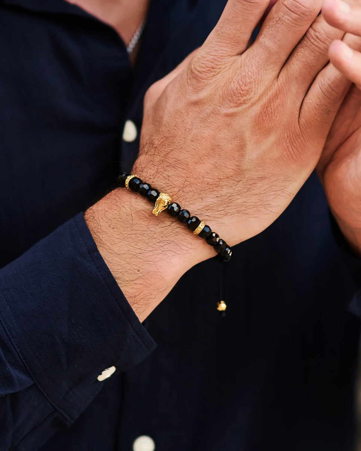 Black onyx beaded bracelet on wrist featuring a gold-toned horse charm