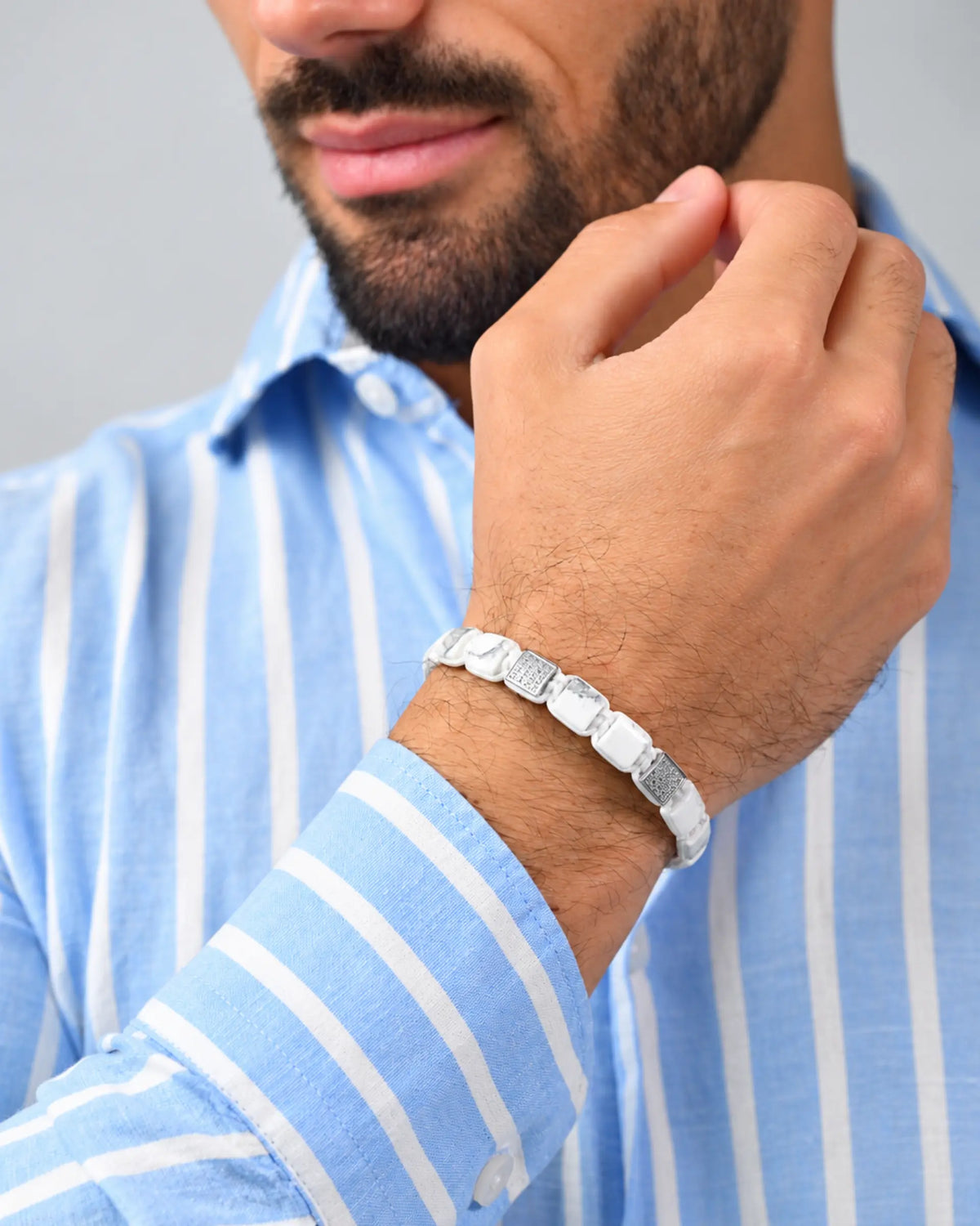 White howlite bead bracelet with gray segments, on man’s wrist