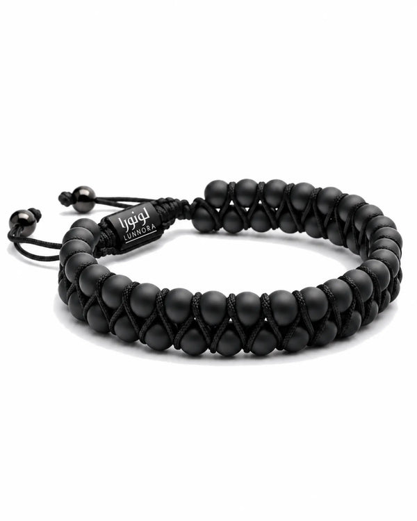 Black braided bracelet with stacked bead links and central woven logo tag