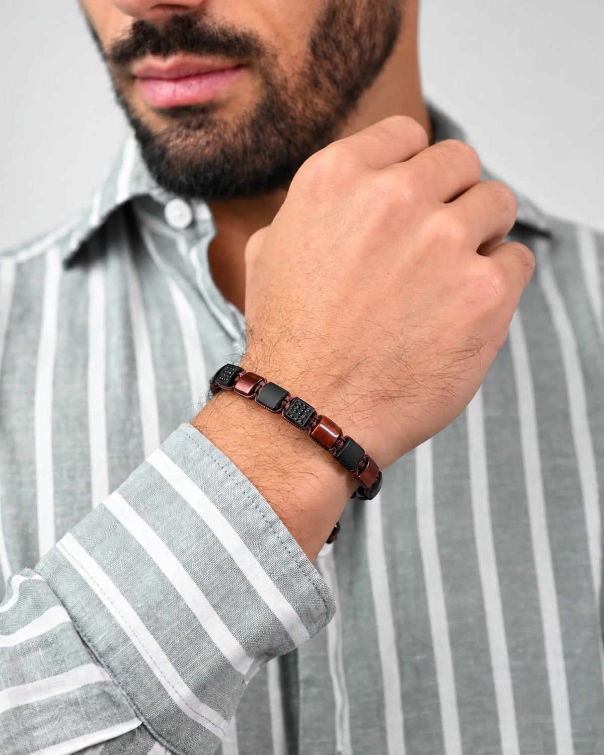 Men's flat bead bracelet with dark red and black beads worn on wrist.