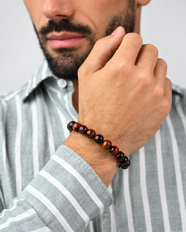 Red and dark tiger eye bead bracelet on man's wrist, braided cord clasp