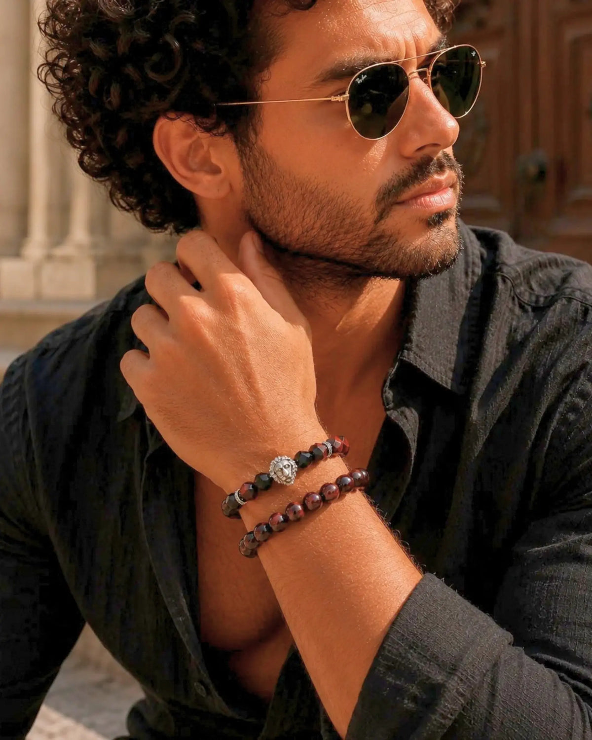 Men's beaded bracelet stack with black cord, tiger-eye beads, and lion charms on wrist