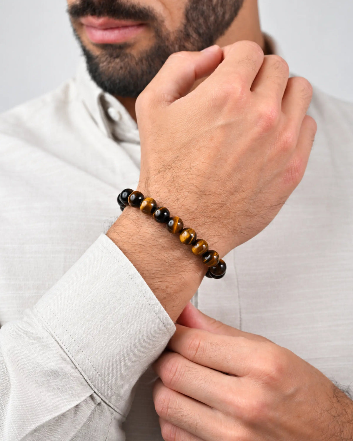 Tiger-eye bead bracelet on wrist with black beads and braided slider tie