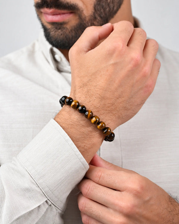 Tiger-eye bead bracelet on wrist with black beads and braided slider tie