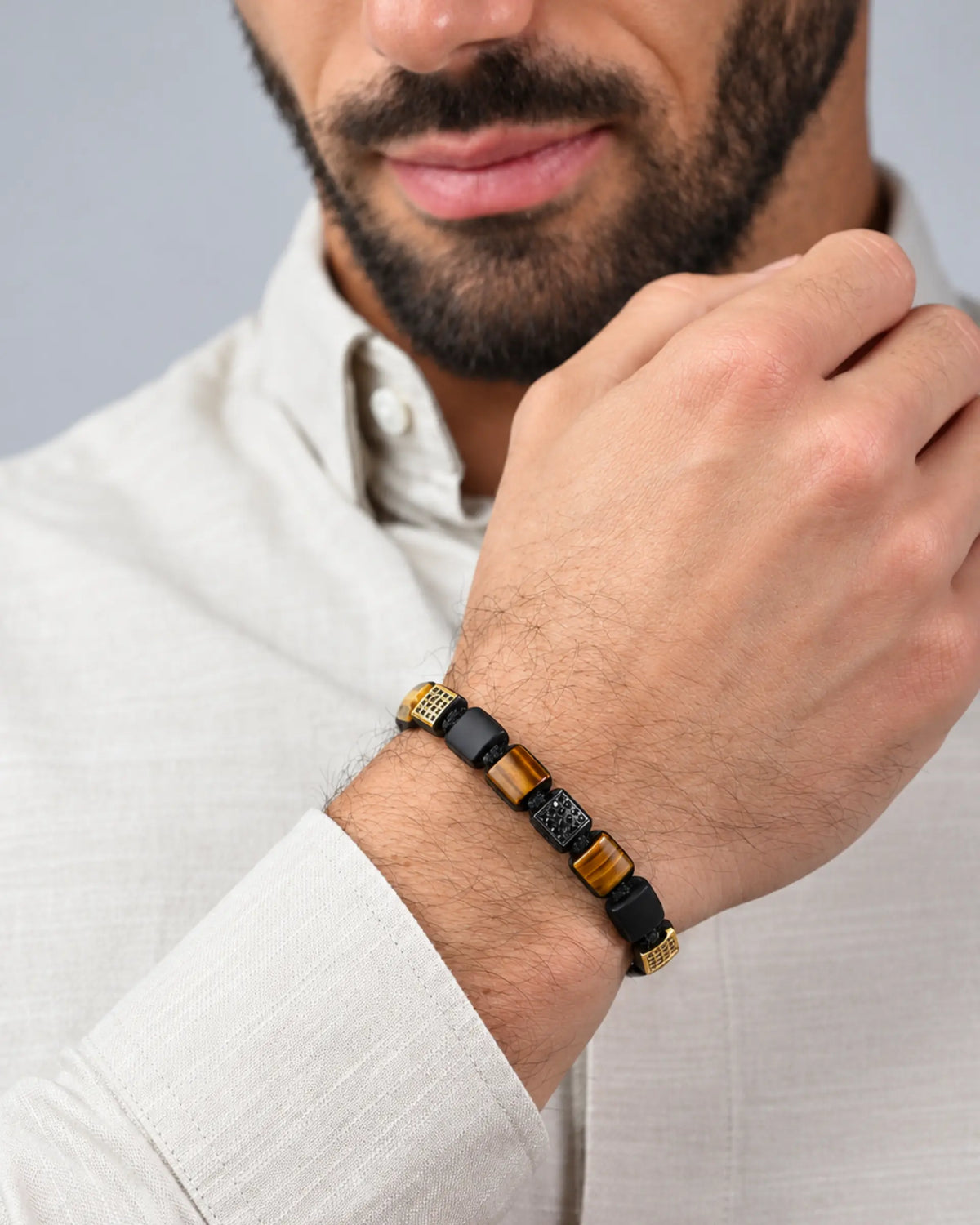 Tiger eye and black onyx bead bracelet with black cord and gold accents on wrist