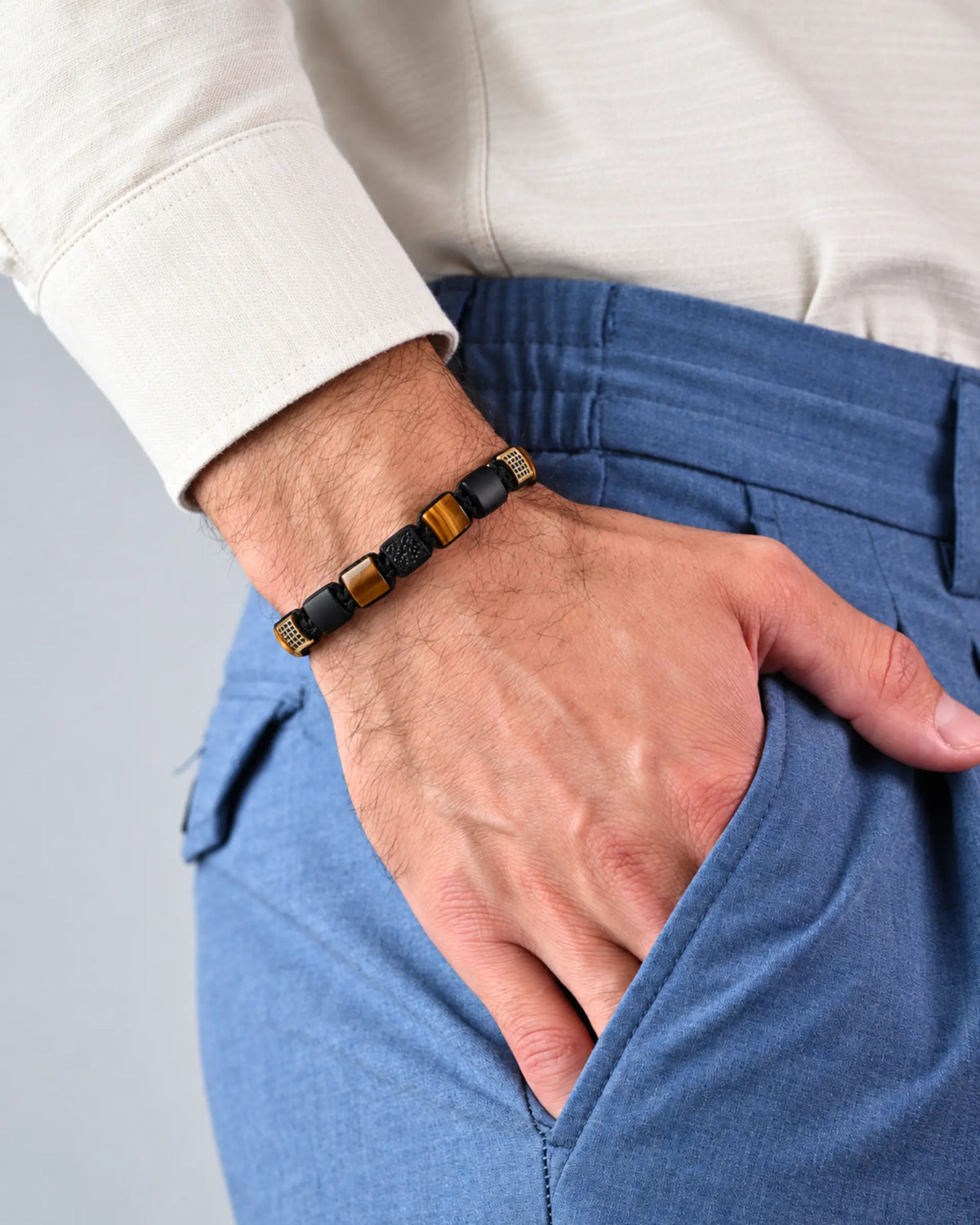 Tiger eye and black bead bracelet on wrist with black cord and gold cube beads